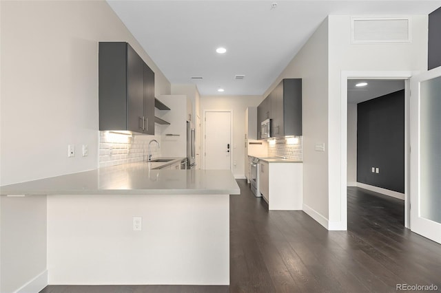 kitchen featuring backsplash, kitchen peninsula, sink, and appliances with stainless steel finishes