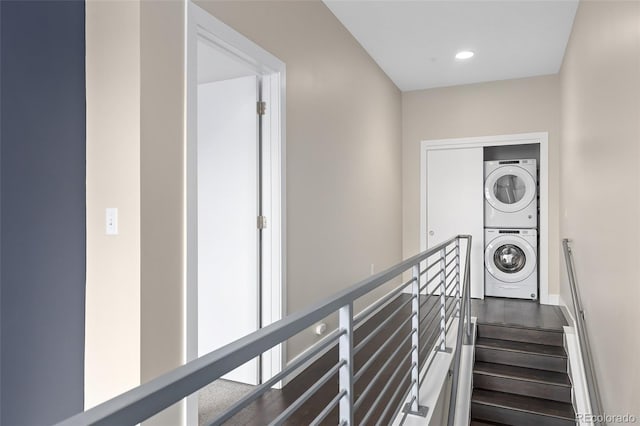 stairway with stacked washer / dryer and wood-type flooring