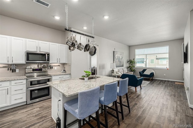 kitchen featuring sink, a kitchen bar, a kitchen island with sink, white cabinets, and appliances with stainless steel finishes