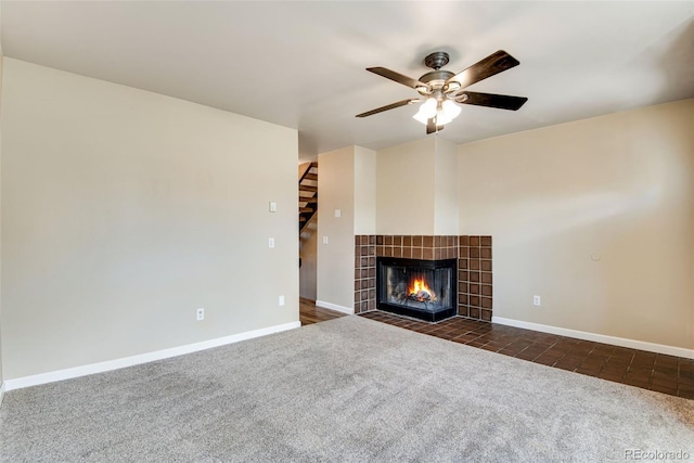 unfurnished living room with dark colored carpet, a ceiling fan, baseboards, and a tile fireplace