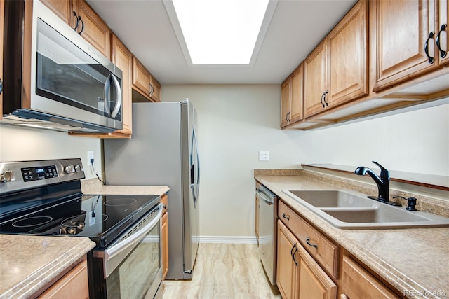 kitchen with a sink, baseboards, stainless steel appliances, and light countertops