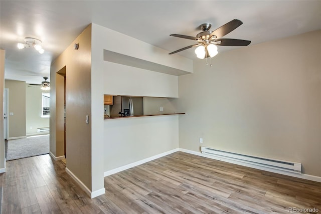 interior space with baseboards, ceiling fan, a baseboard heating unit, and wood finished floors