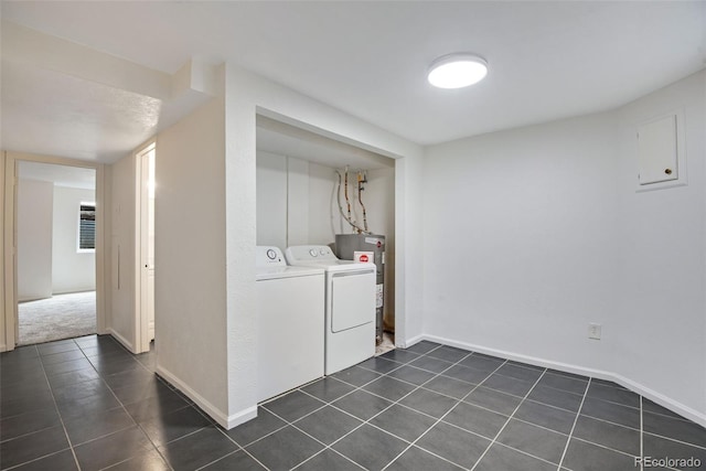 clothes washing area with laundry area, baseboards, dark tile patterned floors, washer and clothes dryer, and water heater