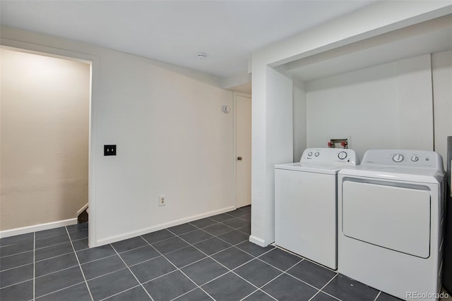 laundry area with dark tile patterned floors, washer and clothes dryer, baseboards, and laundry area