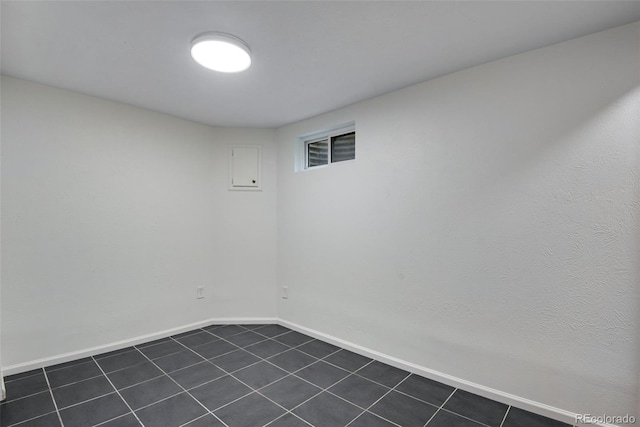 unfurnished room with dark tile patterned flooring and baseboards