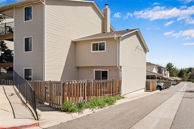 view of side of home featuring a chimney and fence private yard