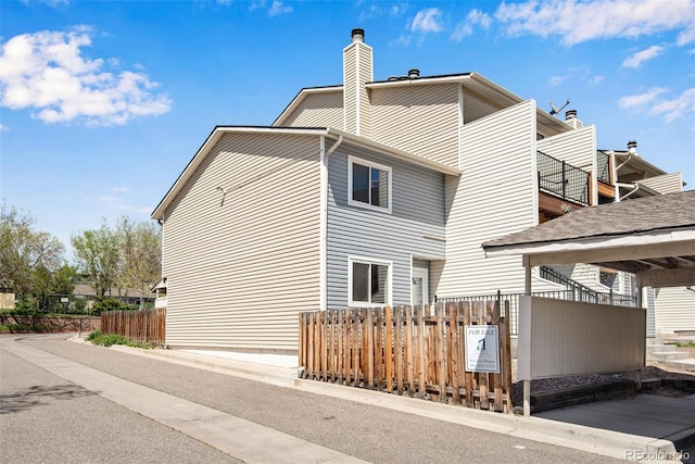 view of home's exterior featuring a chimney and fence private yard