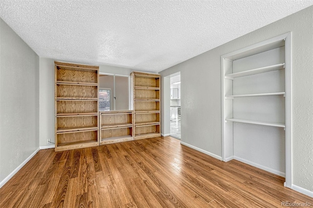 unfurnished living room with wood-type flooring and a textured ceiling