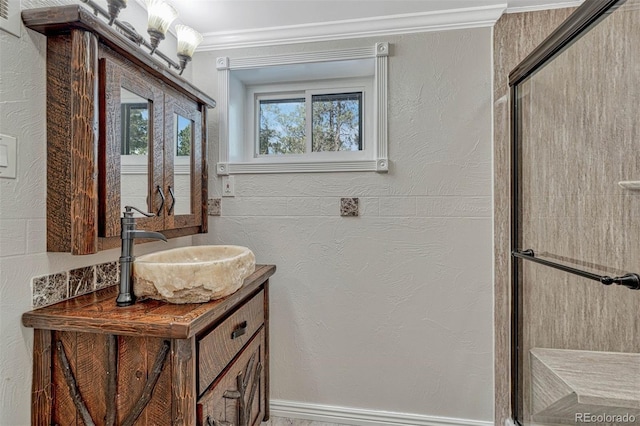 bathroom featuring vanity, a shower with shower door, and ornamental molding