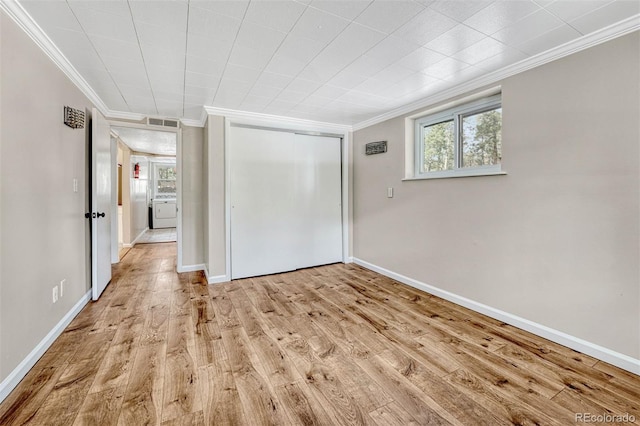 empty room featuring washer / dryer, light hardwood / wood-style floors, and crown molding