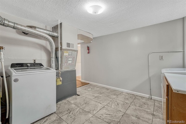 clothes washing area with independent washer and dryer and a textured ceiling