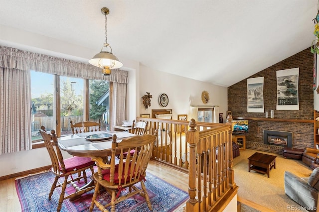 2013 S Holland St, Lakewood, CO 80227 - dining area featuring vaulted ceiling, a brick fireplace, and wood finished floors