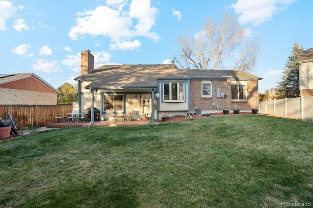 2013 S Holland St, Lakewood, CO 80227 - back of house with a chimney, a patio area, a fenced backyard, and a lawn