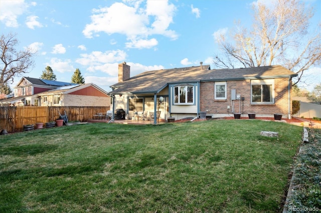 2013 S Holland St, Lakewood, CO 80227 - back of house with a patio area, brick siding, a yard, a fenced backyard, and a chimney