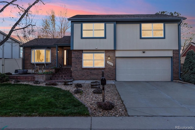 2013 S Holland St, Lakewood, CO 80227 - view of front facade featuring a yard, concrete driveway, an attached garage, and brick siding
