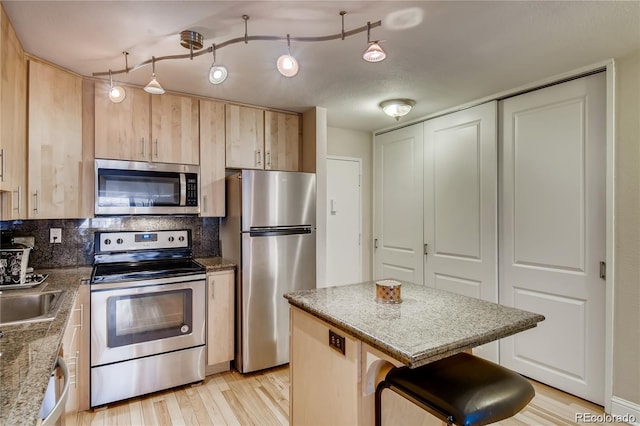 kitchen featuring appliances with stainless steel finishes, tasteful backsplash, light brown cabinets, light hardwood / wood-style floors, and rail lighting