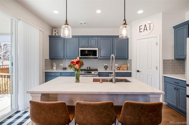 kitchen featuring pendant lighting, a kitchen island with sink, sink, blue cabinetry, and stainless steel appliances