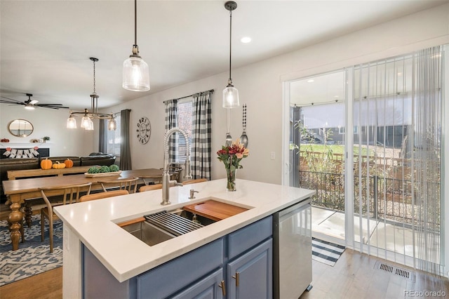 kitchen with decorative light fixtures, an island with sink, and light hardwood / wood-style flooring