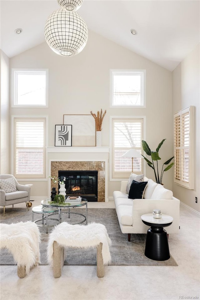 carpeted living room featuring a high ceiling, plenty of natural light, and a premium fireplace