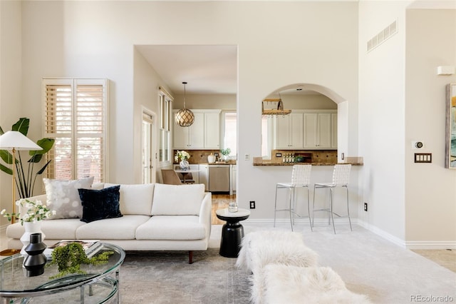 living room featuring light colored carpet and a towering ceiling