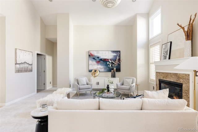 living room featuring light carpet, a premium fireplace, and a towering ceiling