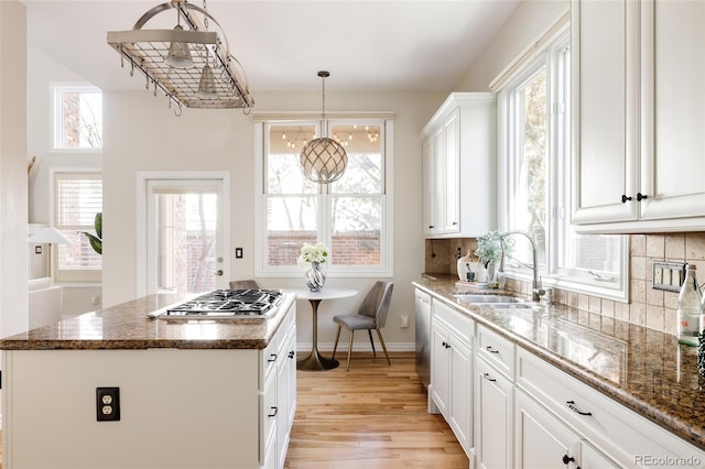 kitchen featuring a center island, decorative light fixtures, white cabinetry, stainless steel appliances, and sink