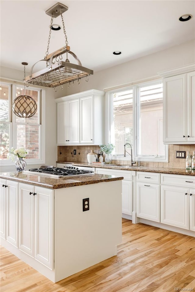 kitchen featuring light hardwood / wood-style flooring, white cabinets, tasteful backsplash, and a center island