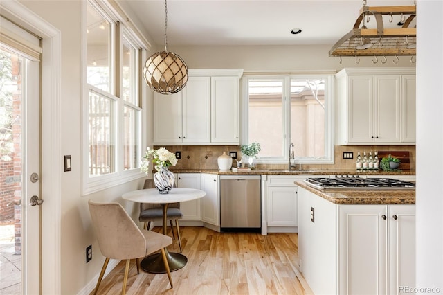 kitchen with white cabinetry, stainless steel appliances, backsplash, hanging light fixtures, and sink