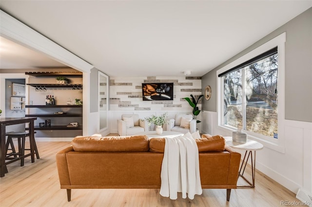 living area featuring an accent wall, a wainscoted wall, and wood finished floors