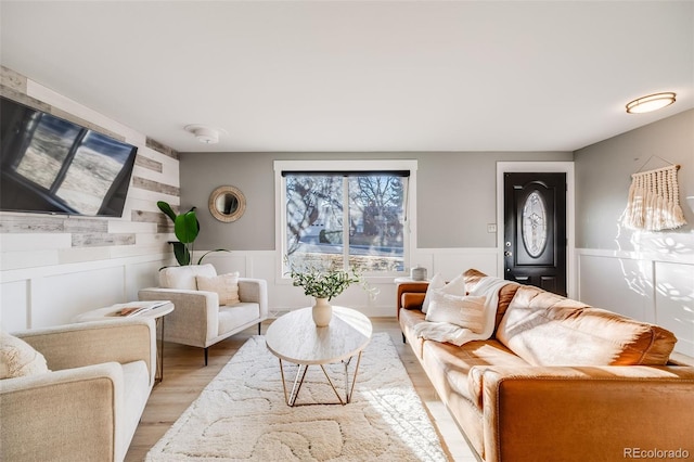 living area featuring light wood finished floors and wainscoting