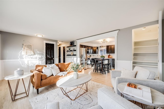 living room with light wood-style floors and a wainscoted wall