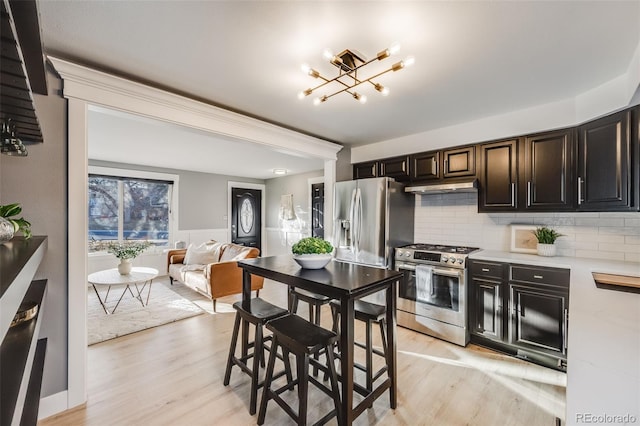 kitchen with stainless steel appliances, light countertops, light wood-style flooring, open floor plan, and under cabinet range hood