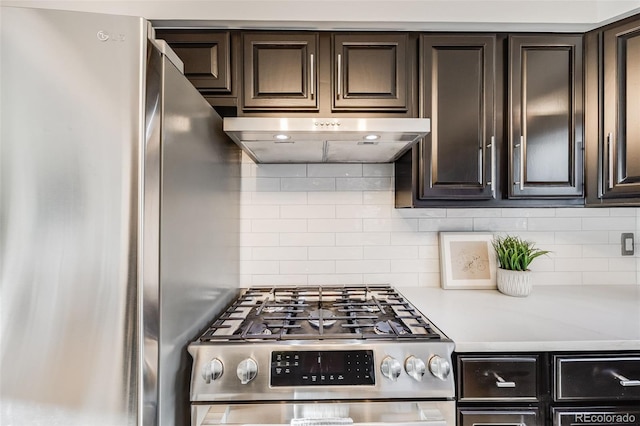 kitchen with appliances with stainless steel finishes, dark brown cabinetry, under cabinet range hood, and tasteful backsplash