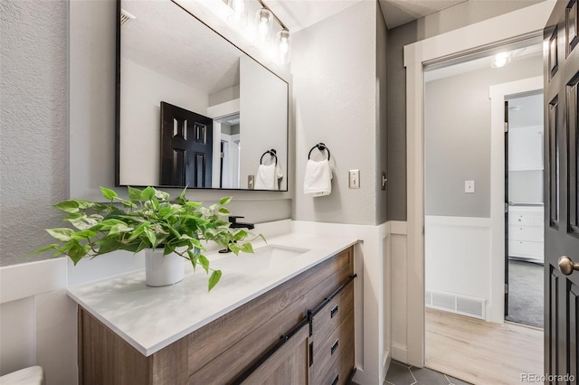 bathroom featuring visible vents, wainscoting, and vanity