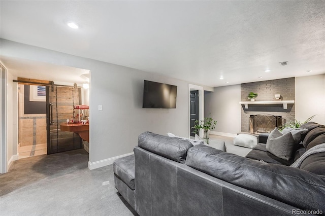 living room featuring carpet floors, a barn door, a brick fireplace, and baseboards