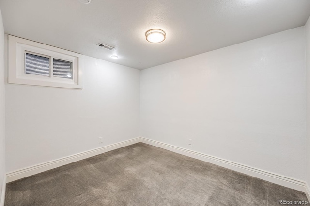 unfurnished room with a textured ceiling, carpet floors, visible vents, and baseboards