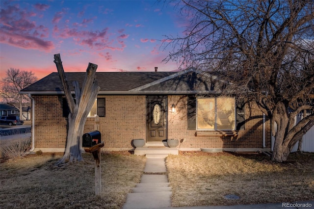 view of front of home with brick siding and roof with shingles