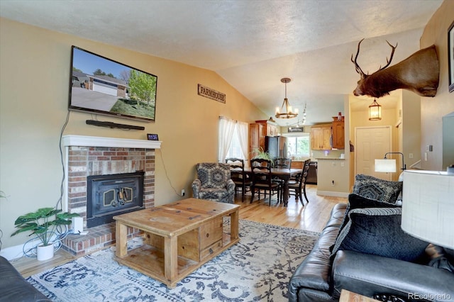8745 W Ottawa Ave, Littleton, CO 80128 - living area with a chandelier, light wood-style flooring, lofted ceiling, and a brick fireplace