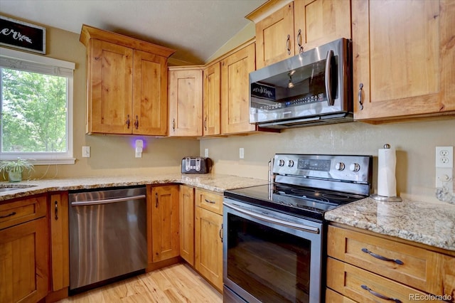 8745 W Ottawa Ave, Littleton, CO 80128 - kitchen featuring stainless steel appliances, lofted ceiling, light wood finished floors, and light stone counters