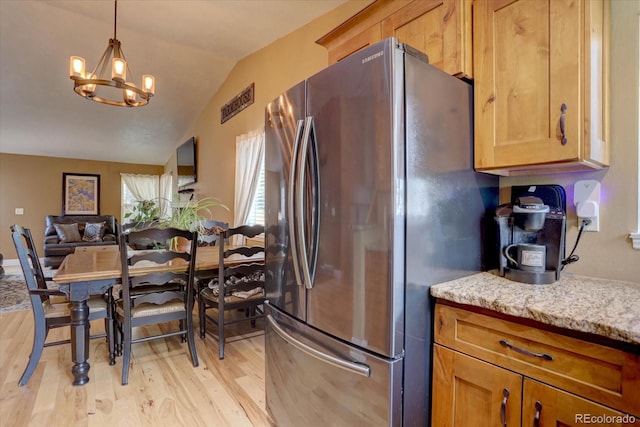 8745 W Ottawa Ave, Littleton, CO 80128 - kitchen featuring freestanding refrigerator, light wood finished floors, a chandelier, lofted ceiling, and light stone countertops