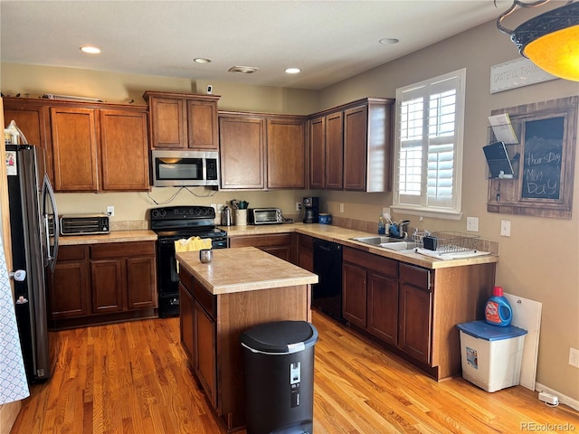 kitchen with a kitchen island, sink, light hardwood / wood-style floors, and black appliances