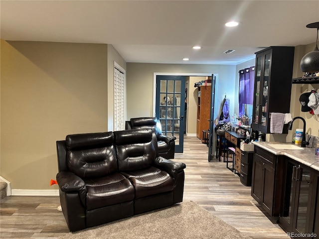 home theater with sink, beverage cooler, and light wood-type flooring