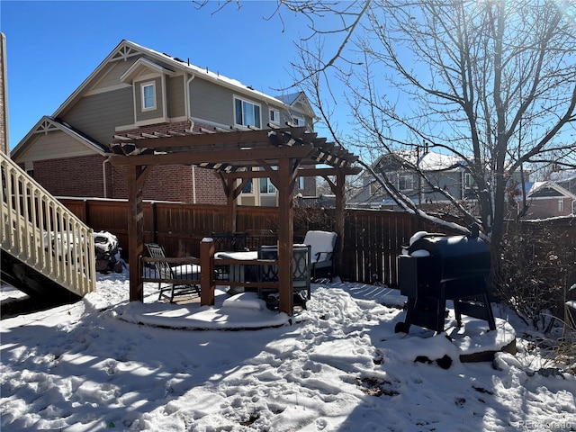 snow covered rear of property with a pergola