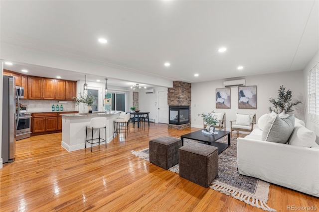 living room with a fireplace, an AC wall unit, and light wood-type flooring