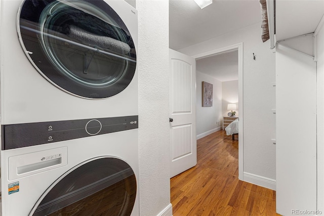 laundry area featuring stacked washing maching and dryer and light hardwood / wood-style floors