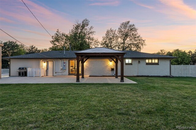 back house at dusk with a patio, a yard, and a gazebo