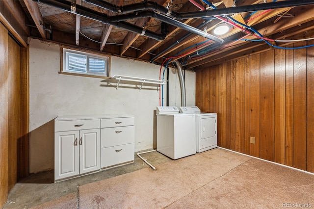 laundry area featuring wooden walls and separate washer and dryer