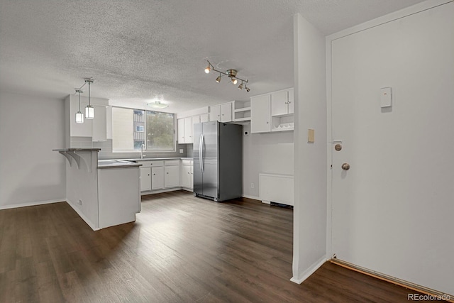 kitchen with kitchen peninsula, stainless steel fridge, decorative light fixtures, white cabinets, and a breakfast bar area