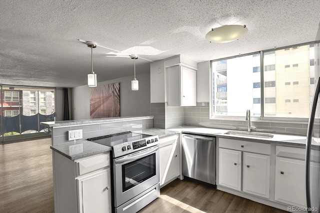 kitchen featuring sink, kitchen peninsula, white cabinetry, stainless steel appliances, and decorative backsplash