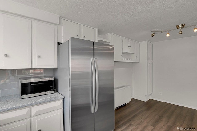 kitchen with dark wood-style floors, appliances with stainless steel finishes, a textured ceiling, white cabinetry, and backsplash